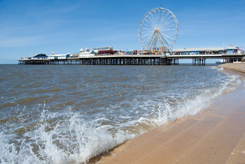 Vista no cais central com parque de diversões e ondas do espirro das escadas, mola ensolarada, costa inglesa ocidental, Blackpool foto de stock Vista no cais central com parque de diversões e ondas do espirro das escadas, mola ensolarada, costa inglesa ocidental, Blackpool foto de stock