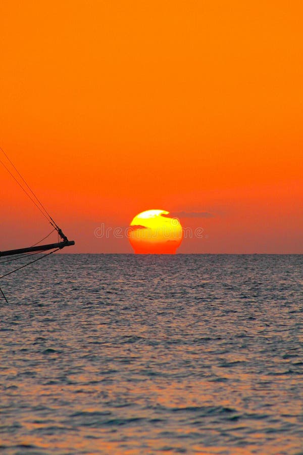 Vista no por do sol da praia das caraíbas com o céu de incandescência vermelho alaranjado e a silhueta preta do barco de navigaçã fotos de stock Vista no por do sol da praia das caraíbas com o céu de incandescência vermelho alaranjado e a silhueta preta do barco de navigaçã fotos de stock