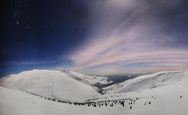 Vista notturna panoramica della valle di montagna invernale coperta da neve, montagne e luna fotografia stock Vista notturna panoramica della valle di montagna invernale coperta da neve, montagne e luna fotografia stock