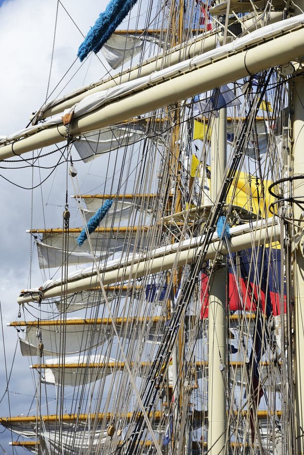 Vista panorámica de los intrincados arcos y velas de un barco alto. Una vista de cierre detallada de los intrincados arcos y velas de un barco alto. la imagen captura una compleja red de poleas y líneas de cuerdas contra un fondo de cielo claro y algunas banderas de señal. el enfoque se centra en el sistema de manipulación de buques que exhibe la artesanía y la estructura de un buque de vela tradicional