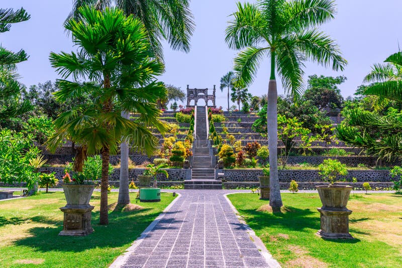 Vista por un largo camino con palmeras y césped cuidado en el parque Ujung Water Palace Ujung, Parque Sukasada en Bali, Indonesia fotos de archivo Vista por un largo camino con palmeras y césped cuidado en el parque Ujung Water Palace Ujung, Parque Sukasada en Bali, Indonesia fotos de archivo