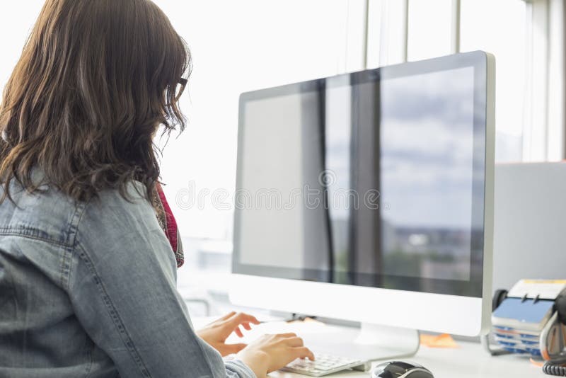 Vista posterior de la empresaria que usa el equipo de escritorio en oficina creativa fotografía de archivo libre de regalías