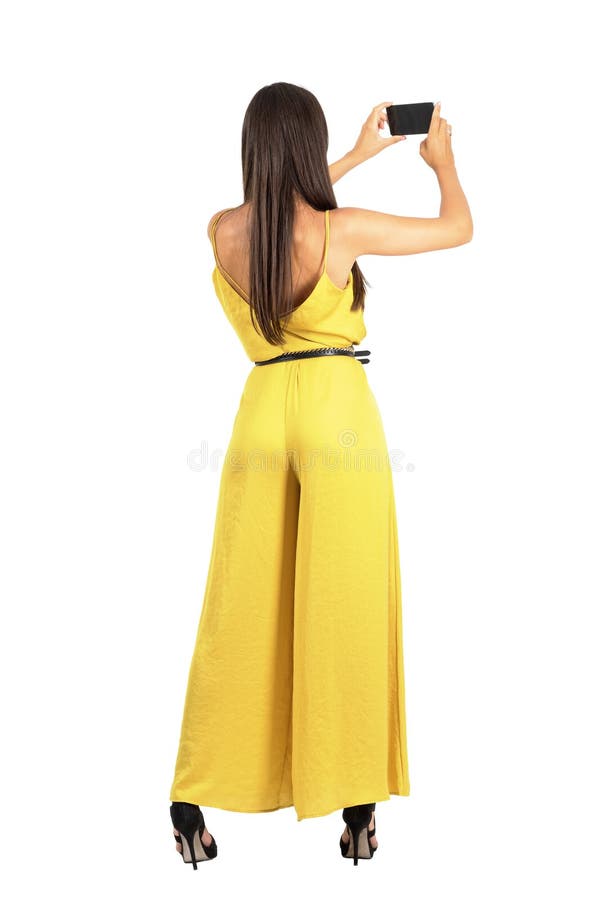 Vista posterior de la mujer elegante joven que toma la foto con smartphone fotos de archivo Vista posterior de la mujer elegante joven que toma la foto con smartphone fotos de archivo