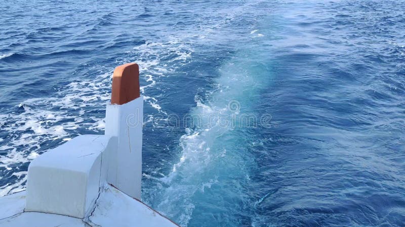 Vista posterior de un barco flotando en un agua azul increíble almacen de video