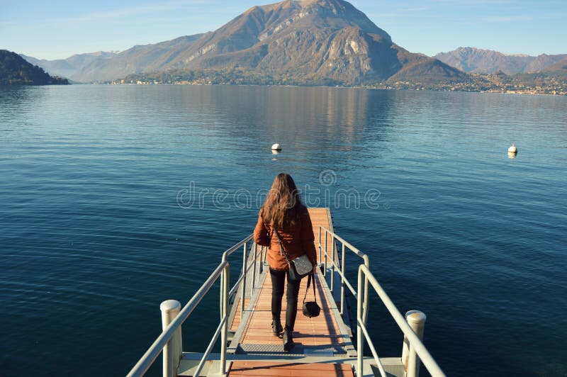 Vista posterior de una mujer illuminada en el embarcadero de Como del lago en Italia imagen de archivo Vista posterior de una mujer illuminada en el embarcadero de Como del lago en Italia imagen de archivo