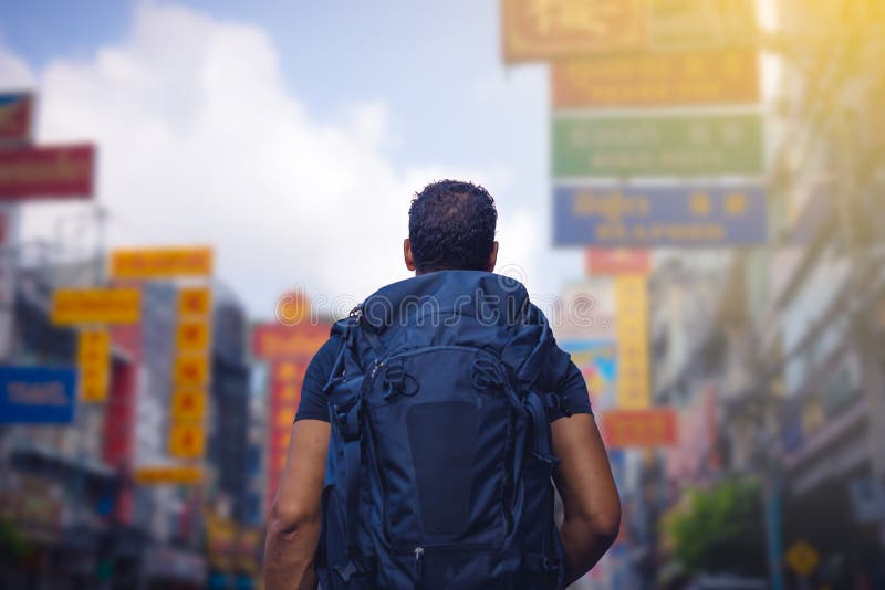 Vista posteriore di un viaggiatore con zaino e sacco a pelo che esamina la strada di Chinatown a Bangkok nella mattina, Tailandia fotografia stock libera da diritti Vista posteriore di un viaggiatore con zaino e sacco a pelo che esamina la strada di Chinatown a Bangkok nella mattina, Tailandia fotografia stock libera da diritti