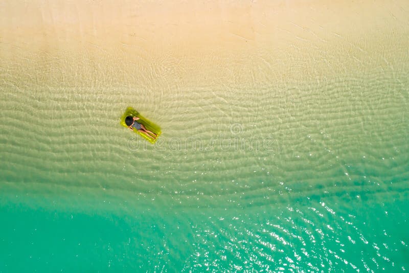 Aerial view of slim woman swimming on the swim mattress in the transparent turquoise sea in Seychelles. Summer seascape with girl, beautiful waves, colorful water. Top view from drone. Aerial view of slim woman swimming on the swim mattress in the transparent turquoise sea in Seychelles. Summer seascape with girl, beautiful waves, colorful water. Top view from drone