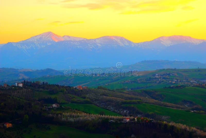 Vista scenica da sopra alle colline e le montagne sotto il cielo giallo di tramonto immagine stock Vista scenica da sopra alle colline e le montagne sotto il cielo giallo di tramonto immagine stock