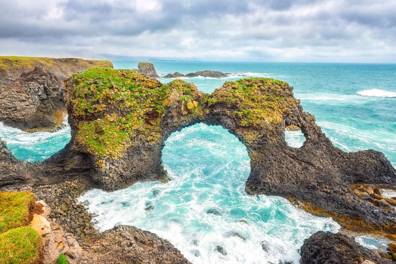 Vista sul mare di stupore, arco naturale alla scogliera vulcanica, costa atlantica, Islanda, fondo del basalto di viaggio fotografie stock libere da diritti Vista sul mare di stupore, arco naturale alla scogliera vulcanica, costa atlantica, Islanda, fondo del basalto di viaggio fotografie stock libere da diritti