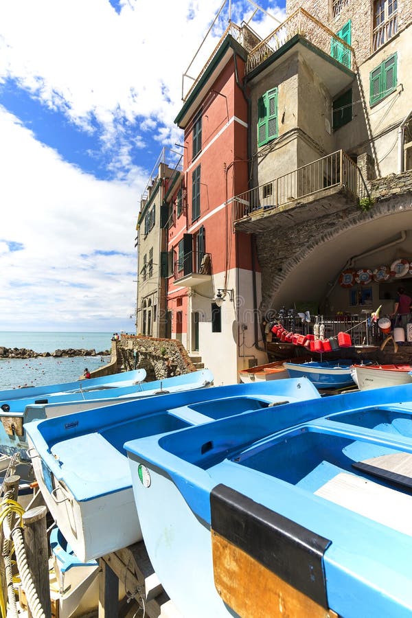 Vista sulla spiaggia e sulle barche blu in piccolo villaggio, Cinque Terre, Riomaggiore, Italia immagine stock