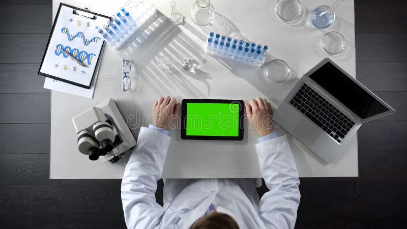 Vista superior de la tableta del movimiento en sentido vertical del técnico de laboratorio con la pantalla verde, laboratorio mod imagenes de archivo Vista superior de la tableta del movimiento en sentido vertical del técnico de laboratorio con la pantalla verde, laboratorio mod imagenes de archivo