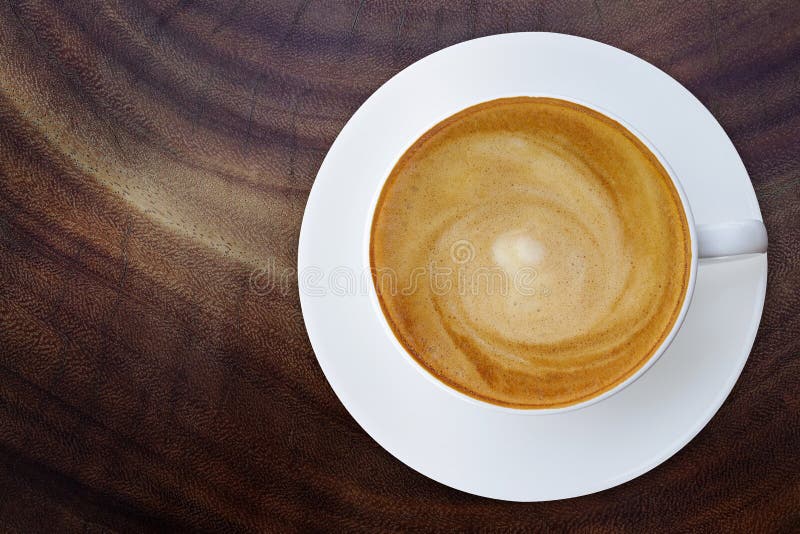 Vista superior de la taza caliente del capuchino del café con el platillo en el textur de madera foto de archivo libre de regalías Vista superior de la taza caliente del capuchino del café con el platillo en el textur de madera foto de archivo libre de regalías