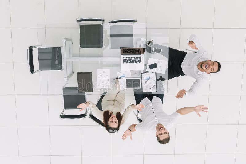 Vista superior Empregados felizes que sentam-se na mesa de escritório fotografia de stock Vista superior Empregados felizes que sentam-se na mesa de escritório fotografia de stock