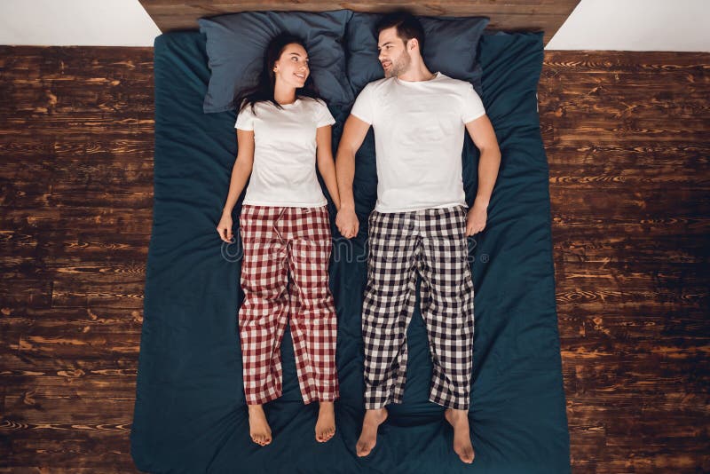 Vista superior O homem considerável e a mulher bonita no pijama encontram-se diretamente cama e olham-se se imagem de stock royalty free Vista superior O homem considerável e a mulher bonita no pijama encontram-se diretamente cama e olham-se se imagem de stock royalty free