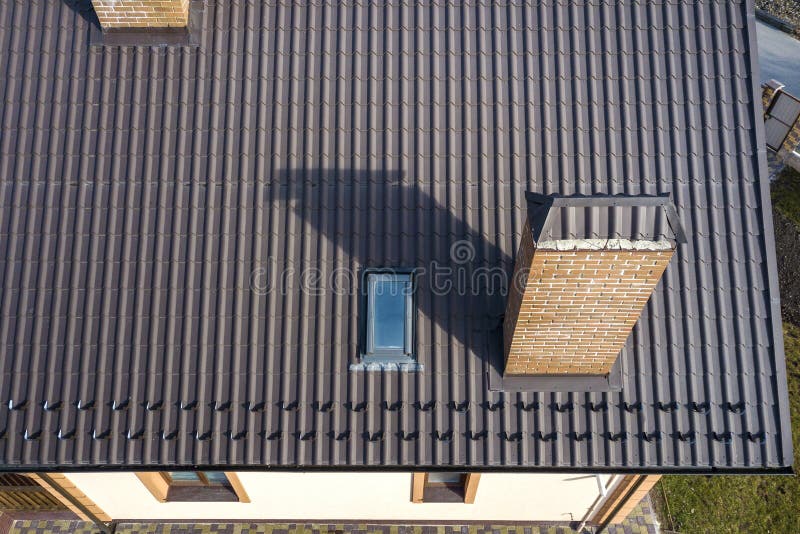 Vista superiore aerea di costruzione il tetto ripido dell'assicella, i camini del mattone e di piccola finestra della soffitta su immagini stock Vista superiore aerea di costruzione il tetto ripido dell'assicella, i camini del mattone e di piccola finestra della soffitta su immagini stock