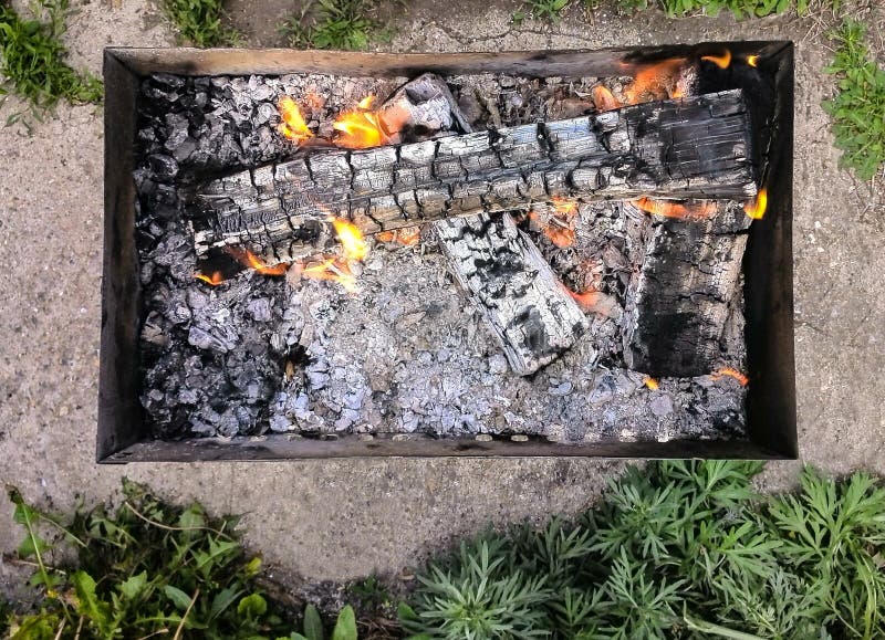 Vista superiore del barbecue portatile di campeggio con le fiamme del fuoco, erba verde del carbone di A intorno immagine stock libera da diritti Vista superiore del barbecue portatile di campeggio con le fiamme del fuoco, erba verde del carbone di A intorno immagine stock libera da diritti
