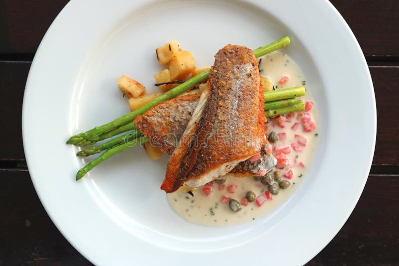 Vista superiore del branzino scottato pentola con la salsa di crema della senape del cappero del pomodoro fotografie stock libere da diritti Vista superiore del branzino scottato pentola con la salsa di crema della senape del cappero del pomodoro fotografie stock libere da diritti