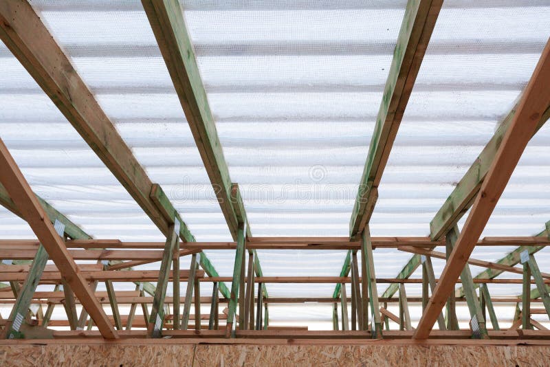 Vista superiore di angolo basso di nuovo tetto di legno con le divisioni e le travi portanti affidabili sotto la membrana antiven immagini stock libere da diritti Vista superiore di angolo basso di nuovo tetto di legno con le divisioni e le travi portanti affidabili sotto la membrana antiven immagini stock libere da diritti