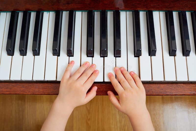Vista superiore di una mano, una tastiera di piano del bambino La mano o del piccolo bambino immagine stock libera da diritti Vista superiore di una mano, una tastiera di piano del bambino La mano o del piccolo bambino immagine stock libera da diritti