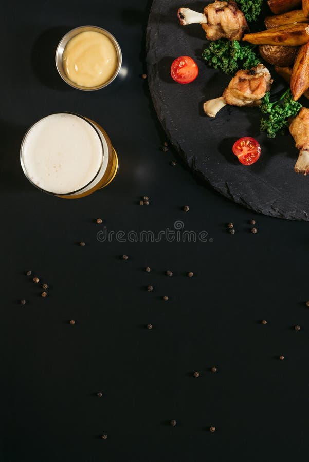vista superiore di vetro di birra, di salsa e delle patate al forno saporite con le ali di pollo fritto fotografia stock libera da diritti vista superiore di vetro di birra, di salsa e delle patate al forno saporite con le ali di pollo fritto fotografia stock libera da diritti
