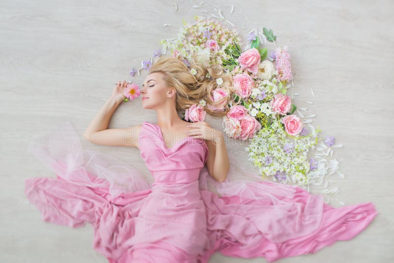 VISTA SUPERIORE: Ritratto di una ragazza con occhi chiusi in un vestito rosa su un pavimento con fiori fotografie stock VISTA SUPERIORE: Ritratto di una ragazza con occhi chiusi in un vestito rosa su un pavimento con fiori fotografie stock