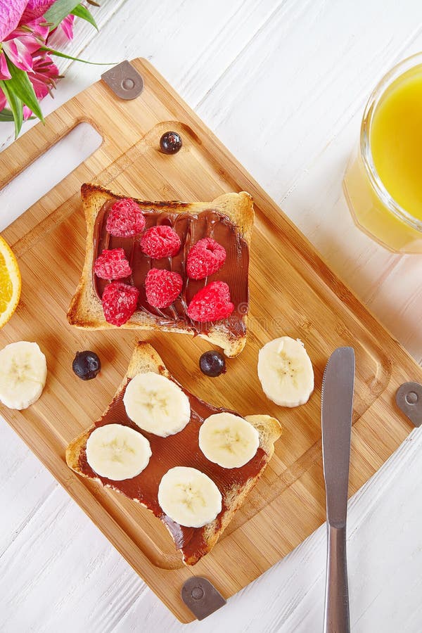 Vista superiore su pane tostato con burro di arachidi ed i lamponi, banana La composizione nella prima colazione pone pianamente fotografia stock Vista superiore su pane tostato con burro di arachidi ed i lamponi, banana La composizione nella prima colazione pone pianamente fotografia stock