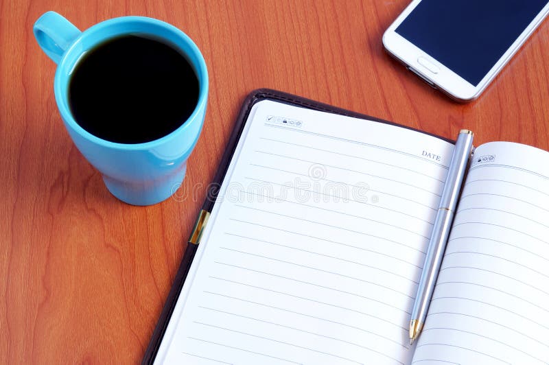 Vista superiore sul taccuino, sullo smartphone, sulla penna e sulla tazza di caffè aperti fotografia stock