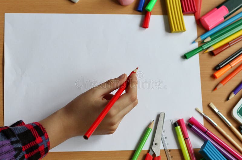 Vista superiore sulla tavola con il foglio bianco di carta e della mano del bambino con la matita Di nuovo al banco Il colore dip immagini stock libere da diritti Vista superiore sulla tavola con il foglio bianco di carta e della mano del bambino con la matita Di nuovo al banco Il colore dip immagini stock libere da diritti