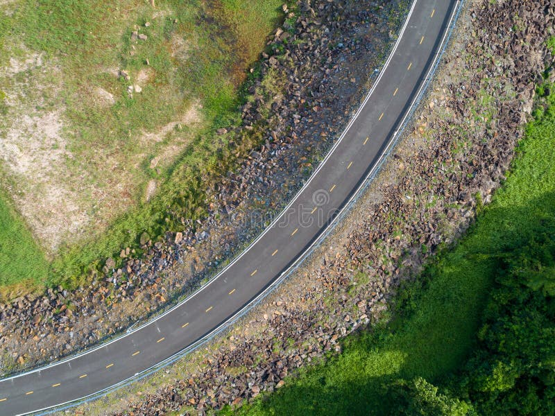 Vista superiore una strada d'avvolgimento vuota del catrame con gli alberi verdi e bordo della strada del OM dell'erba dalla vist fotografia stock Vista superiore una strada d'avvolgimento vuota del catrame con gli alberi verdi e bordo della strada del OM dell'erba dalla vist fotografia stock