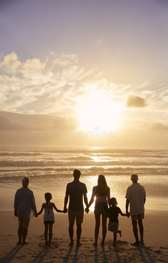 Vista traseira da multi família da geração mostrada em silhueta na praia fotografia de stock Vista traseira da multi família da geração mostrada em silhueta na praia fotografia de stock