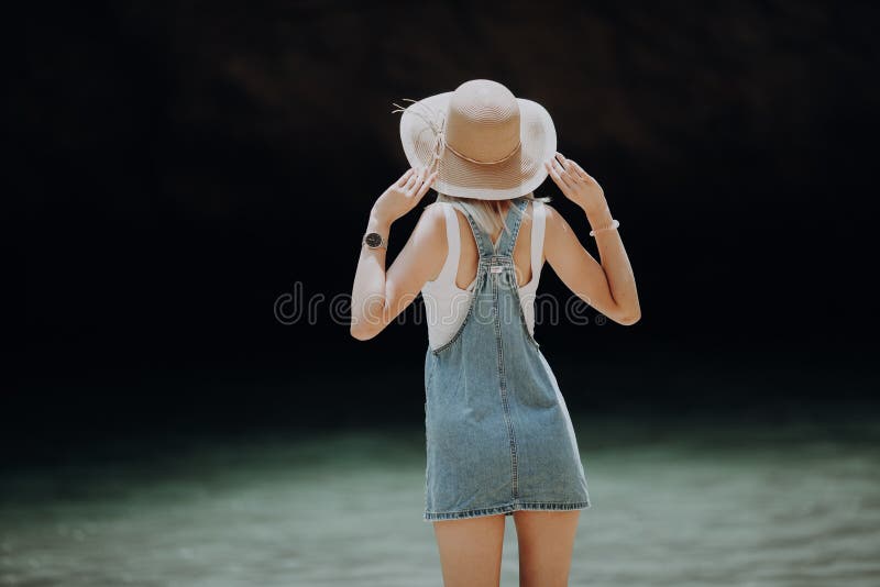 Vista traseira de um chapéu vestindo da mulher que aprecia a vista no oceano foto de stock royalty free Vista traseira de um chapéu vestindo da mulher que aprecia a vista no oceano foto de stock royalty free