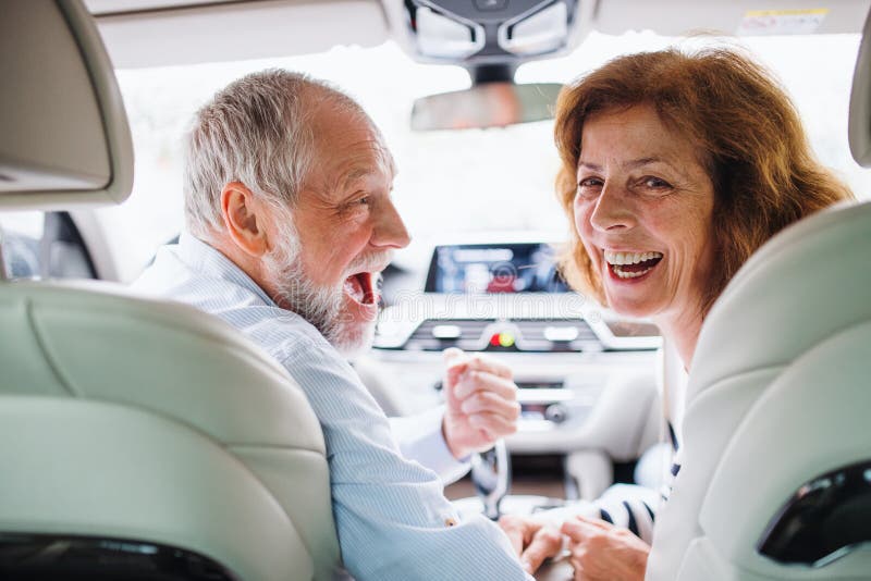 Vista traseira do casal feliz sentado no carro, olhando para trás imagens de stock Vista traseira do casal feliz sentado no carro, olhando para trás imagens de stock