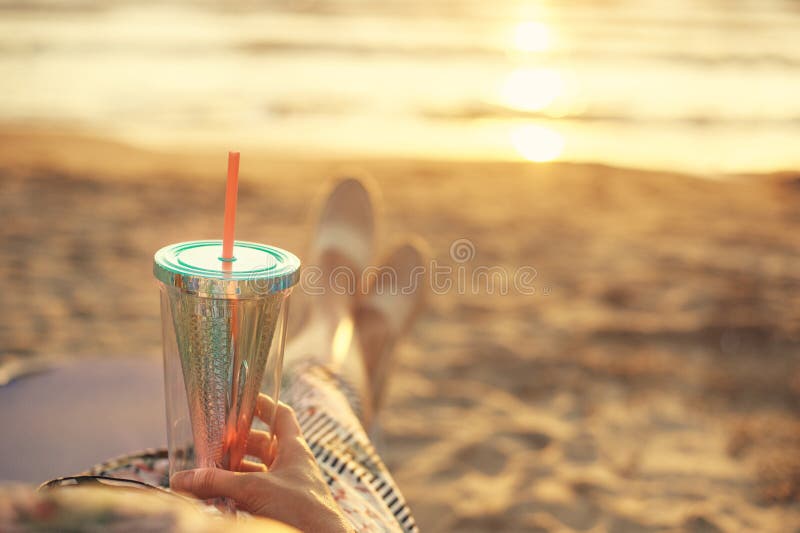 Vista traseira em uma mulher que aprecia o por do sol com o cocktail em Albânia na costa arenosa do mar de adriático foto de stock royalty free Vista traseira em uma mulher que aprecia o por do sol com o cocktail em Albânia na costa arenosa do mar de adriático foto de stock royalty free
