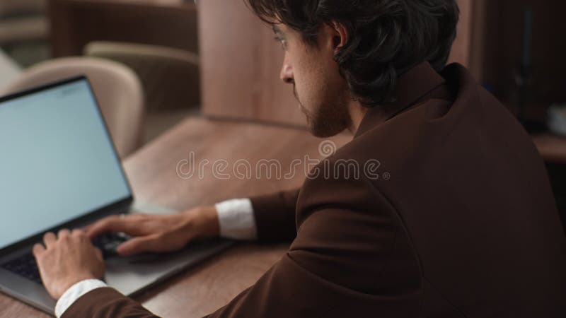 Vista traseira fechada do empresário cansado em terno formal que sofre de dor no pulso enquanto trabalha no laptop sentado em