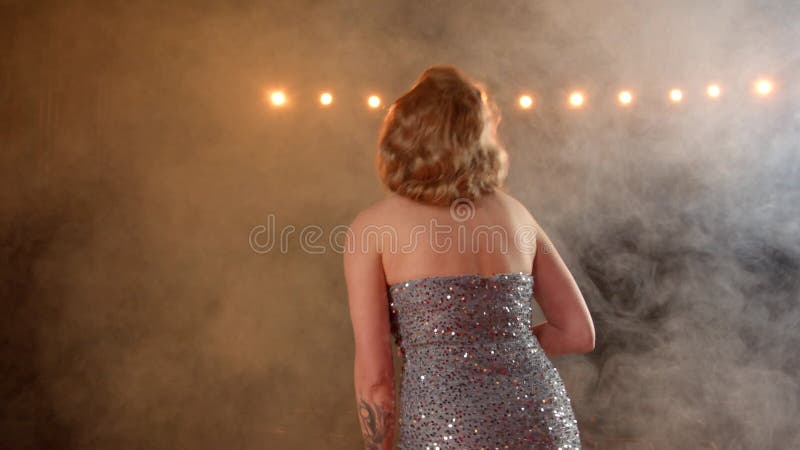 Vista trasera de cantante femenina expresando gratitud a la multitud emocionada luego del espectáculo metrajes