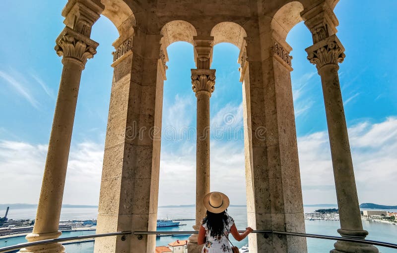 Vista trasera de la mujer mirando la asombrosa vista de la ciudad de dividida a través de columnas de campanario de la catedral. imágenes de archivo libres de regalías