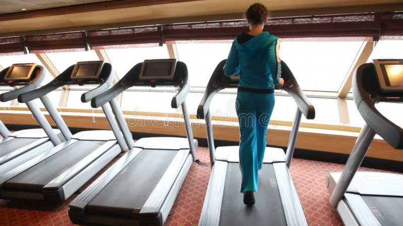 Vista trasera de una mujer delgada corriendo en el gimnasio en los pies metrajes