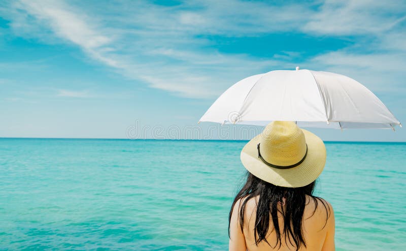 Vista trasera del traje de ba?o asi?tico del desgaste de mujer y del paraguas blanco del control de la mano en la playa tropical fotos de archivo libres de regalías Vista trasera del traje de ba?o asi?tico del desgaste de mujer y del paraguas blanco del control de la mano en la playa tropical fotos de archivo libres de regalías
