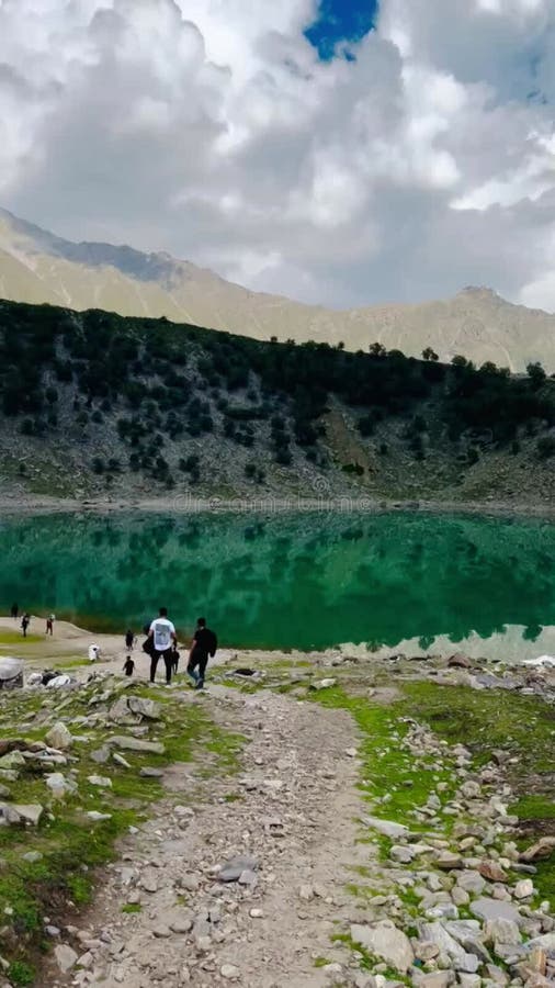 Vista trasera del turista caminando hacia el lago al pie del lago y la montaña almacen de video