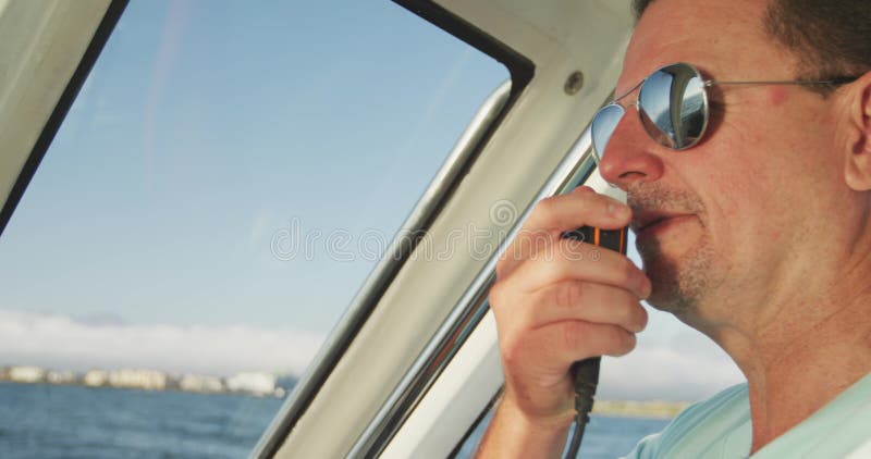 Vista à retaguarda de um homem caucasiano a bordo de um barco com walkietalkie