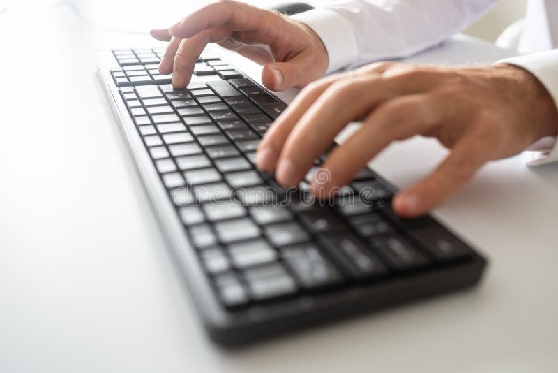 Visualizzazione del primo piano delle mani maschii facendo uso della tastiera di computer nera fotografia stock Visualizzazione del primo piano delle mani maschii facendo uso della tastiera di computer nera fotografia stock