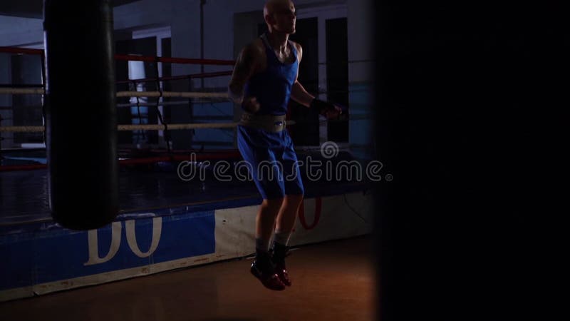 Visão remota de saltos de boxe masculinos fortes saltando pulando corda esquentando antes do treino de boxe no clube esportivo