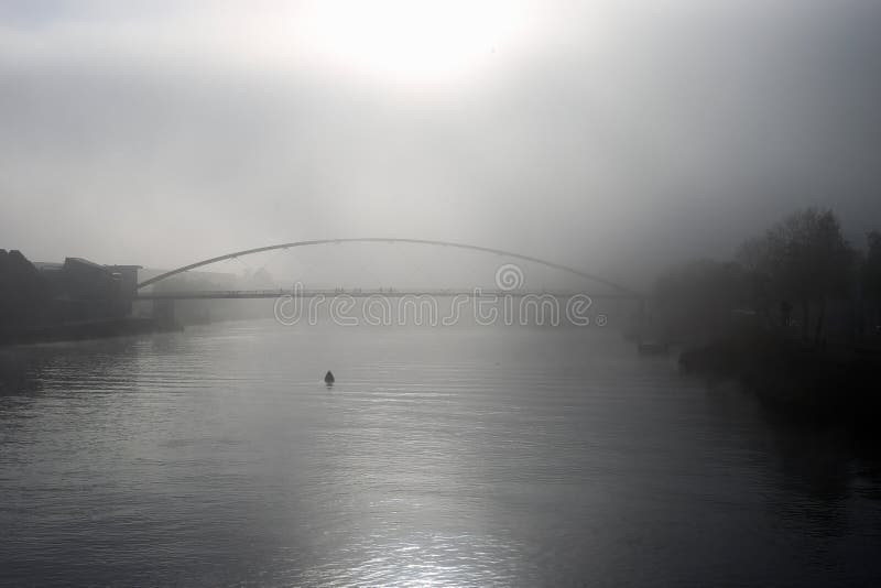 Visão turva limitada sobre o rio Maas, com neblina grossa na silhueta da ponte e na beira do rio na luz do sol da manhã cedo fotos de stock Visão turva limitada sobre o rio Maas, com neblina grossa na silhueta da ponte e na beira do rio na luz do sol da manhã cedo fotos de stock