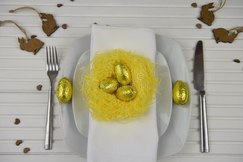 Vit för inbrott för påsktabellställe med det gula handgjorda redet och guld- färgägg med wood garneringar för kaninkanin royaltyfri fotografi Vit för inbrott för påsktabellställe med det gula handgjorda redet och guld- färgägg med wood garneringar för kaninkanin royaltyfri fotografi