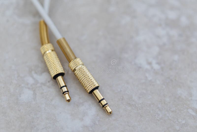 Vit ljudsignal kabel med guld- metall på en marmorbakgrund fotografering för bildbyråer Vit ljudsignal kabel med guld- metall på en marmorbakgrund fotografering för bildbyråer