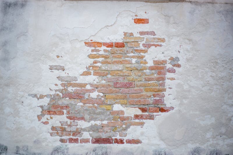 A wall of brick on which stucco partially peeled off. A wall of brick on which stucco partially peeled off