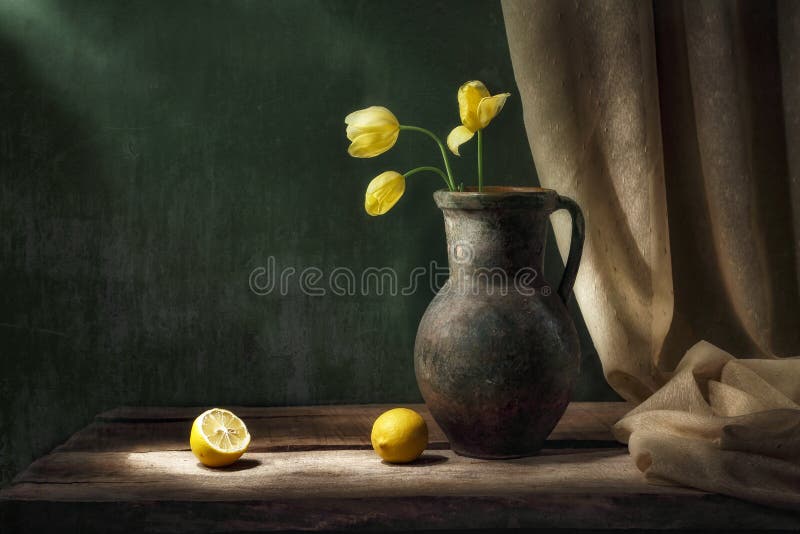 Vita classica con bouquet di tre fiori di tulipano giallo nella vecchia brocca di vintage due frutti di limone tagliati e avannott fotografie stock