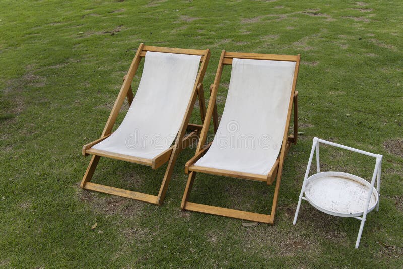 Vita däcksstolar på gräsmattan i trädgården arkivfoton
