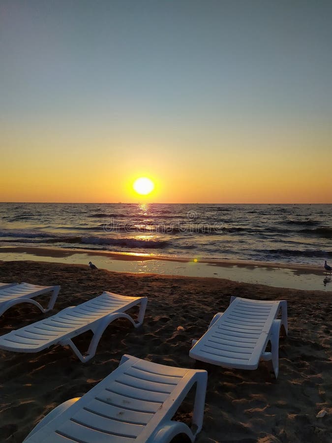 Vita däcksstolar på stranden i marknadssolens strålar royaltyfria bilder