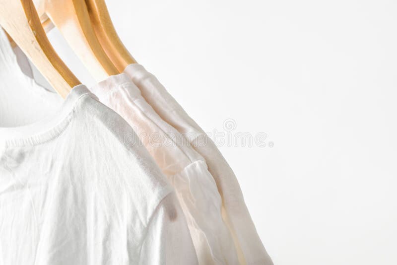 Vita rena bomullsT-tröja som hänger på trähängare på en kugge i garderob Vit v?ggbakgrund Tillfällig unisex- kläder arkivfoton Vita rena bomullsT-tröja som hänger på trähängare på en kugge i garderob Vit v?ggbakgrund Tillfällig unisex- kläder arkivfoton